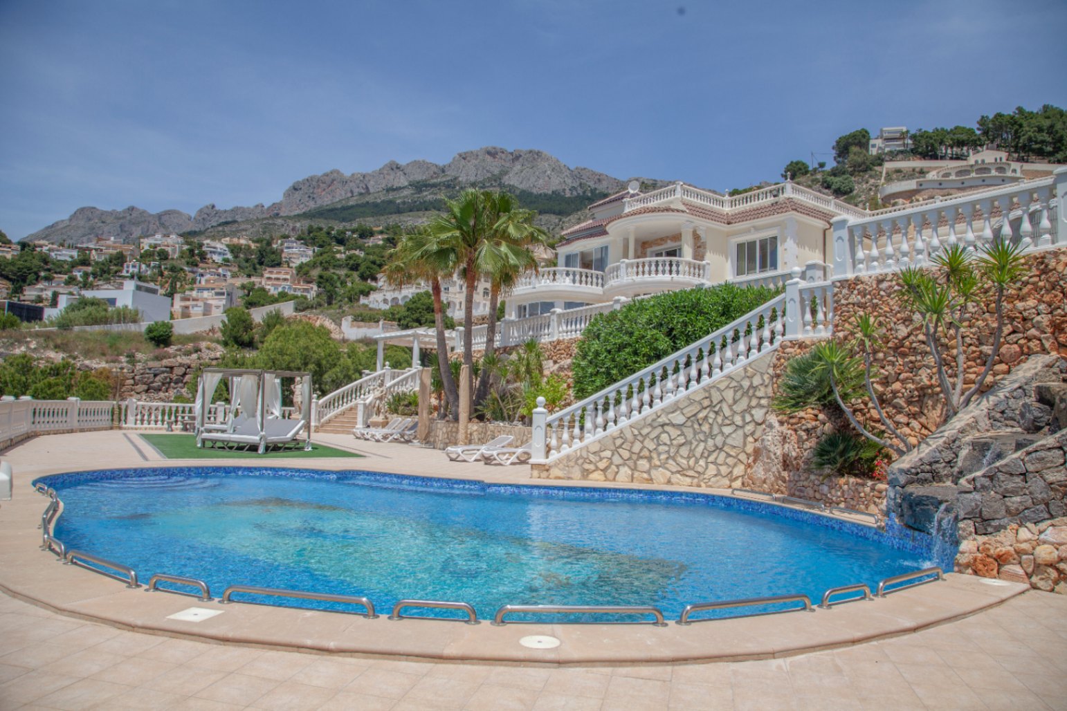 For sale an exquisite complex consisting of two majestic villas in the picturesque town of Altea, an oasis of tranquility on the resplendent Costa Blanca, just 60 km from Alicante airport. The main villa, with an imposing area of 749 m2, stands as a symbol of elegance and comfort. Upon entering, there is a lobby that leads to a living room luxuriously furnished with luxury furniture, adorned with gold-plated elements that reflect a refined and exclusive taste. The meticulously designed UK kitchen and dining set are true masterpieces, while the office offers a private and elegant workspace. On the ground floor, a guest bedroom with a private bathroom and a games room complete this leisure and relaxation area. On the first floor, a welcoming hallway leads to a second living room, creating an atmosphere of serenity and comfort. The master bedroom, a dream suite, features an exquisitely appointed bathroom with china items and a walk-in closet with private bathroom. Additionally, 3 additional bedrooms with en-suite bathrooms provide an intimate space for family and guests. The crown jewel of this property is its large 199 m2 terrace, with panoramic views of the Mediterranean Sea and creates a perfect environment for outdoor entertaining and relaxing moments. On an expansive 6,173 m2 plot, there is an impressive swimming pool and solarium, surrounded by gardens that offer an oasis of tranquility and privacy. In addition, a 537 m2 guest villa, currently under construction, which has 5 bedrooms and 6 bathrooms, a spa area with swimming pool and 1 gym, completes this enclave of opulence and distinction.